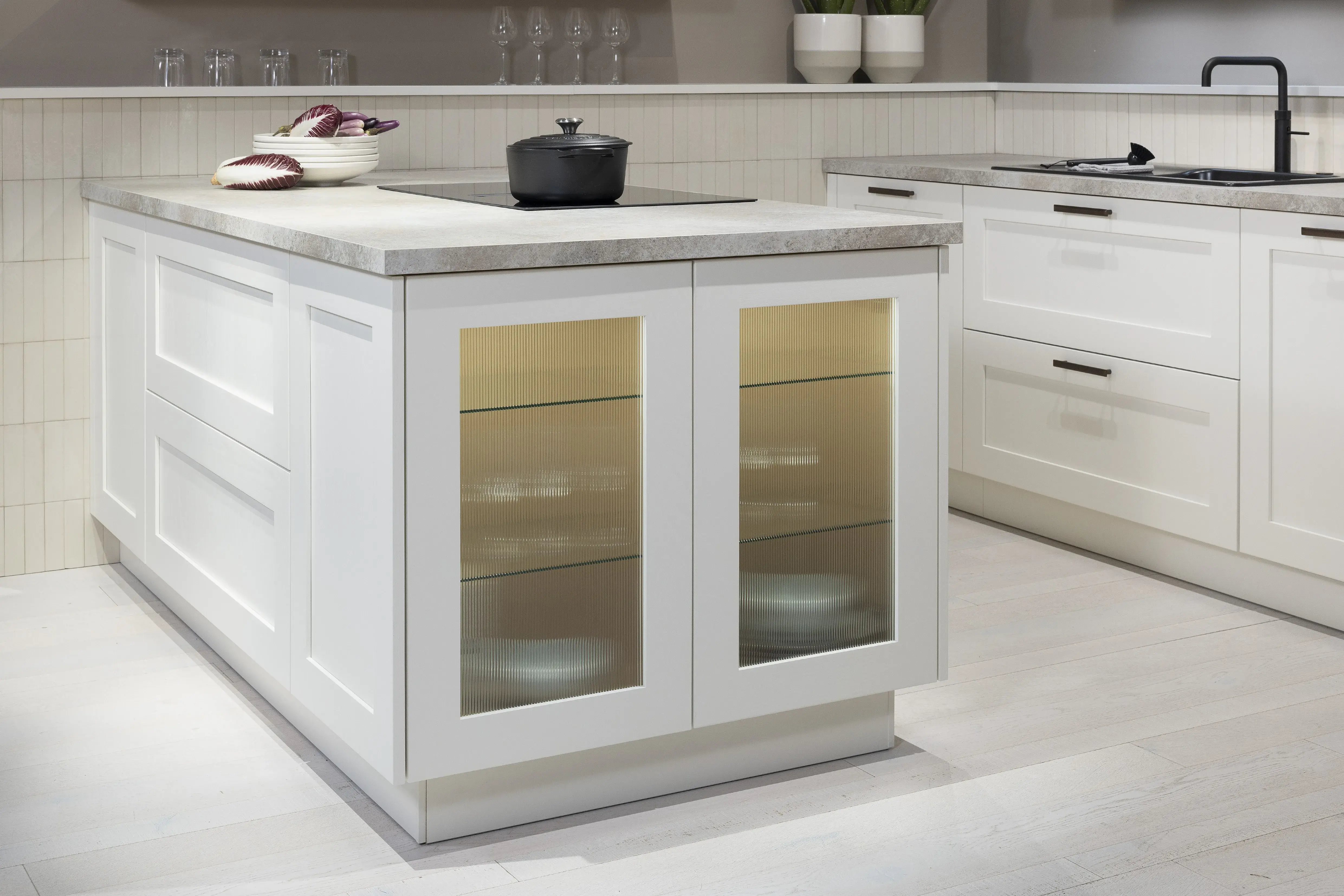 APL: 15 Kalkstein Repro 25 mm Front: AV 6055 Weiß Echtholz lackiert,  Front 2: AV 6082 Wildeiche-natur Korpus: 2085 Designkorpus Feineiche-natur Griff: 515 Metall Bronze-dunkel Geräte: Bosch  Armatur: Quooker Spüle: Systemceram   Features: Landhausküche modern, Echtholz RAL und NCS lackierbar, Riffelglasvitrine, Beleuchtung, schwebender Block, Echtholzfurnier lackiert kombiniert mit Echtholzfurnier, Fliesen, Korpus Echtholz Feineiche Natur, Griffe in Bronze. 