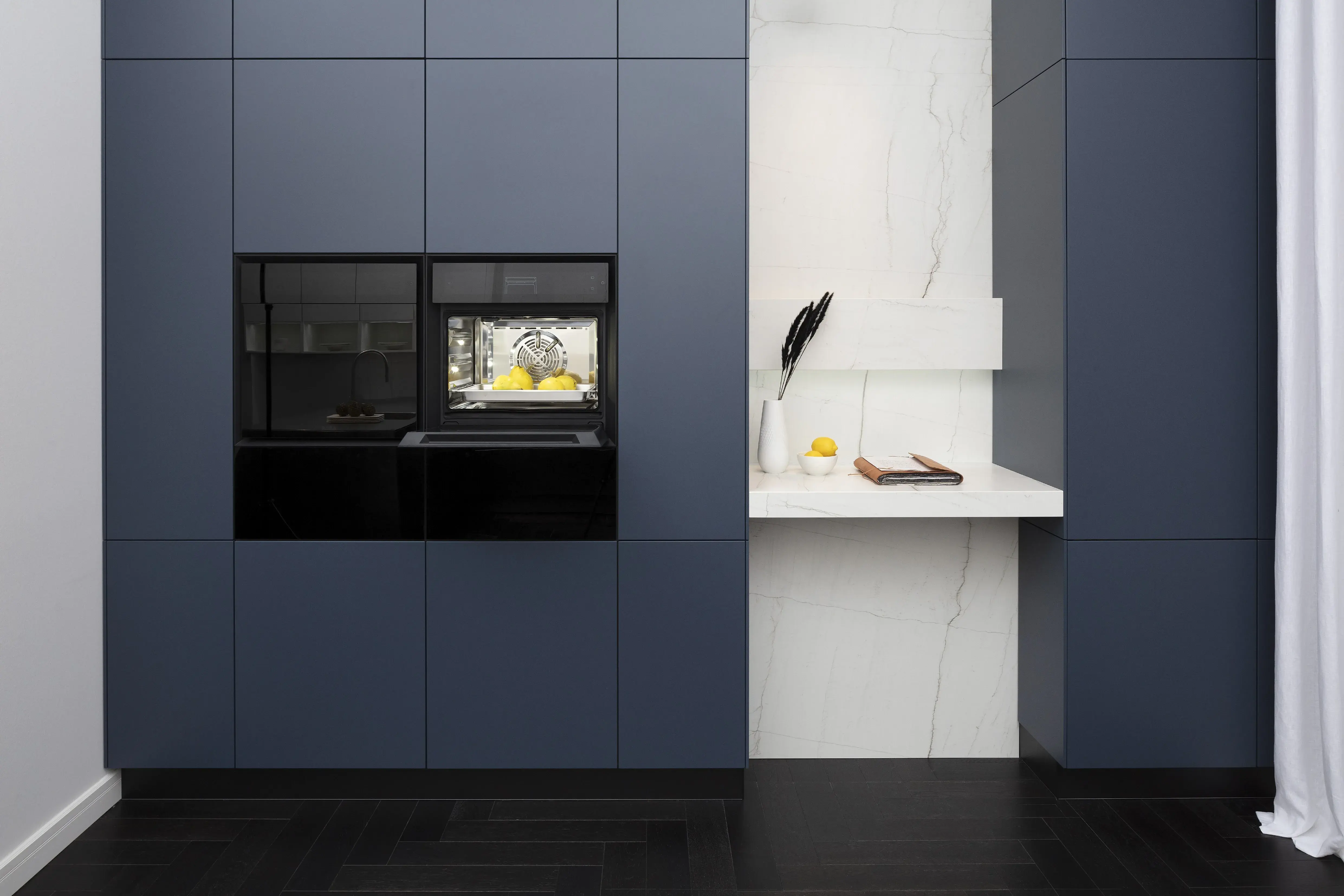 Front: Industriestahl Metalliclack geschliffen AV6000 NCS Mattlack APL: Franke Edelstahl 6 mm Geräte: Bora Spüle Armaturen: Franke  Features: Metallfront, Spülbecken in APL integriert (aus einem Guss), Oberschränke mit Lowboard-Charakter, integrierter Arbeitsplatz, dunkler Korpus mit Aluminium-Abschlussleiste, Wärmeschublade mit Gittereinsatz.